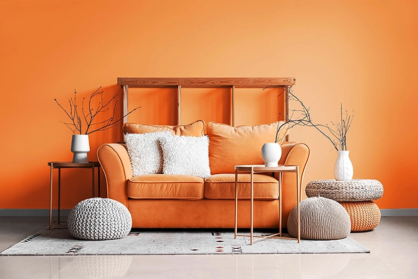 Modernes Interieur eines Wohnzimmers mit Couch und Poufs an der orangen Wand